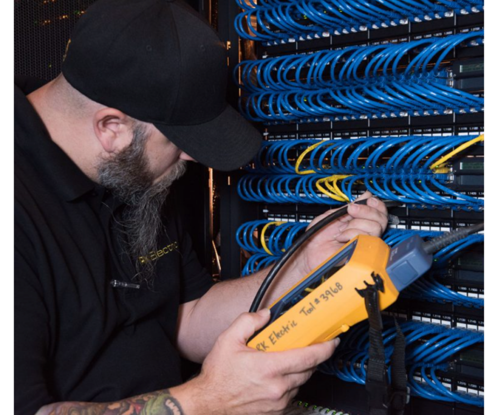 Electrical services technician performing preventative maintenance on a data center electrical box.